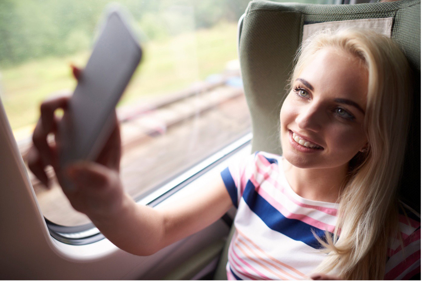 Eine Frau sitzt mit ihrem Smartphone in der Bahn
